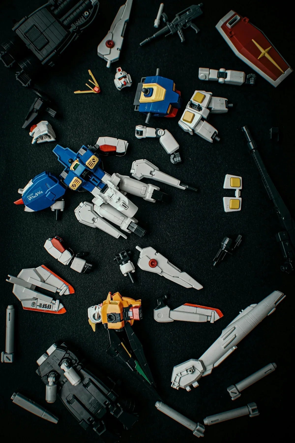 Färgglada byggdelar till Gundam-robotleksak på svart bakgrund, nördpryl hos Nerdbutiken.