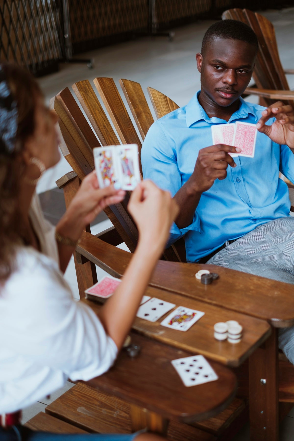 man in blue button up shirt holding playing cards
