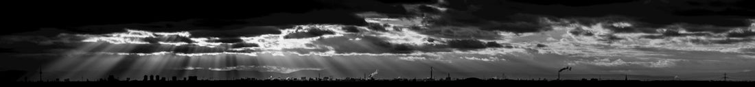 a black and white photo of the sun shining through clouds