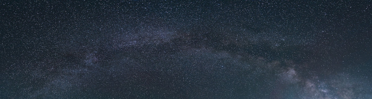 a group of people standing on top of a hill under a night sky filled with