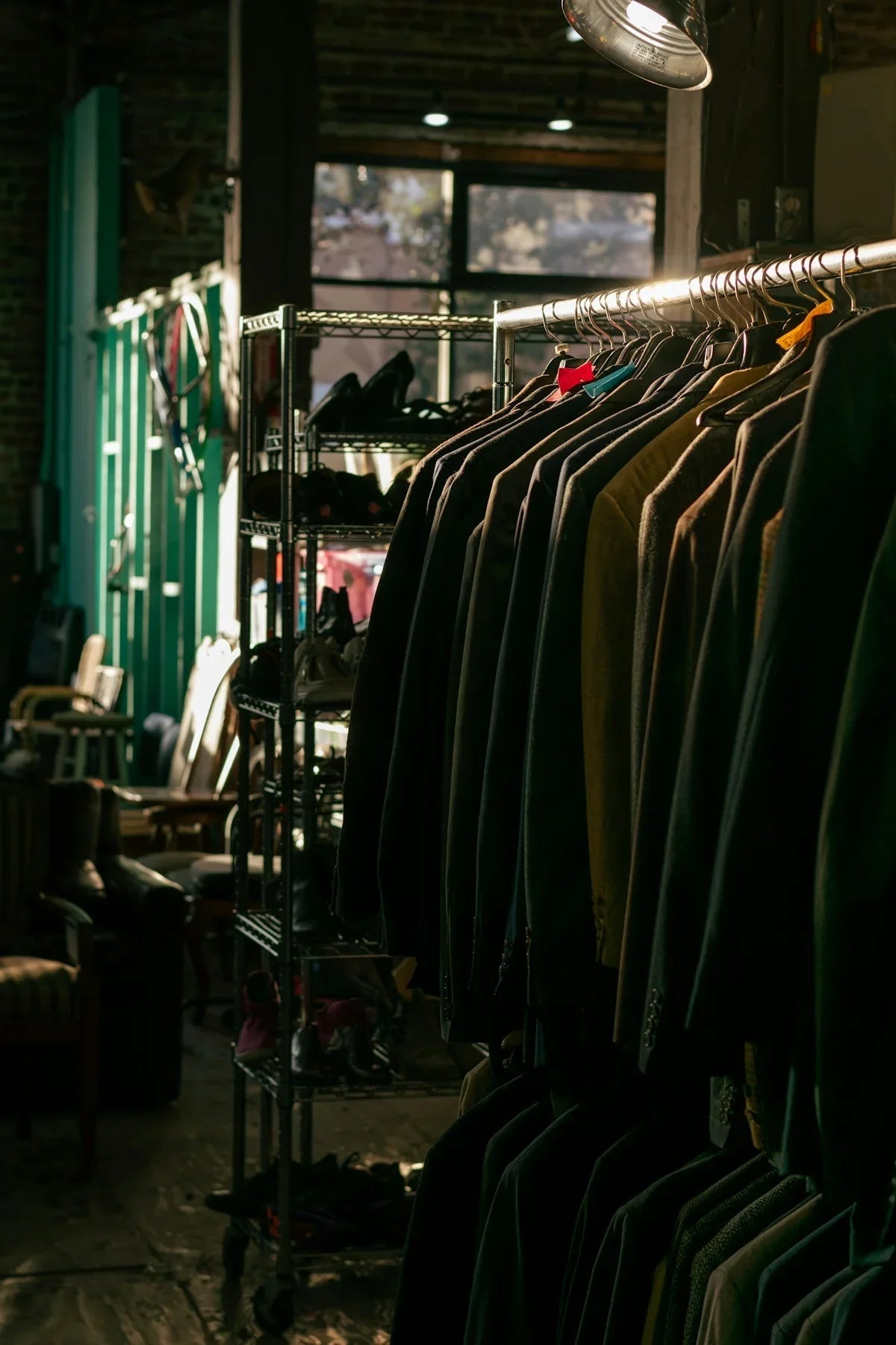 Klädställ med kostymer och skor i en vintagebutik med industriell inredning