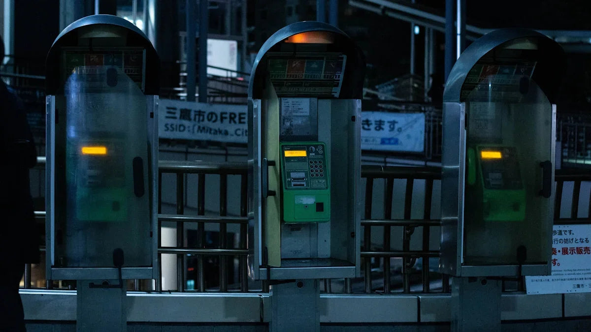 Tre gröna japanska telefonautomater utomhus på natten, retro teknik Nerdbutiken