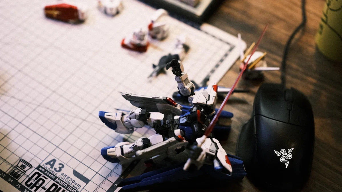 Gundam-robotmodell på byggmatta bredvid gamingmus, nördiga prylar på skrivbord hos Nerdbutiken.