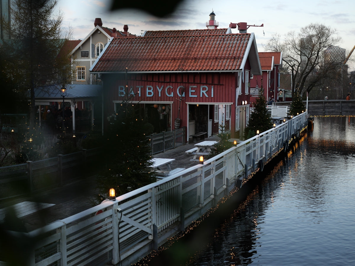 a red building with a white fence next to a body of water