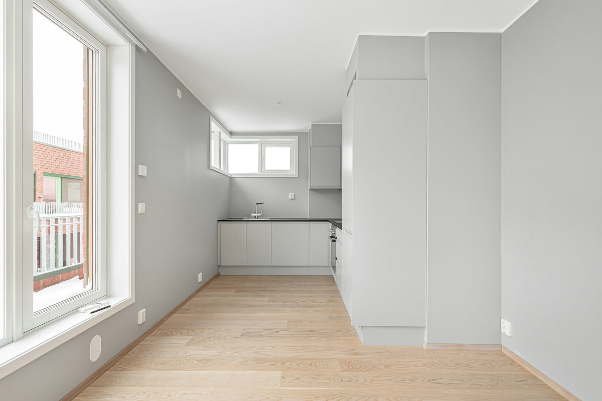 An empty room with a wooden floor and white walls