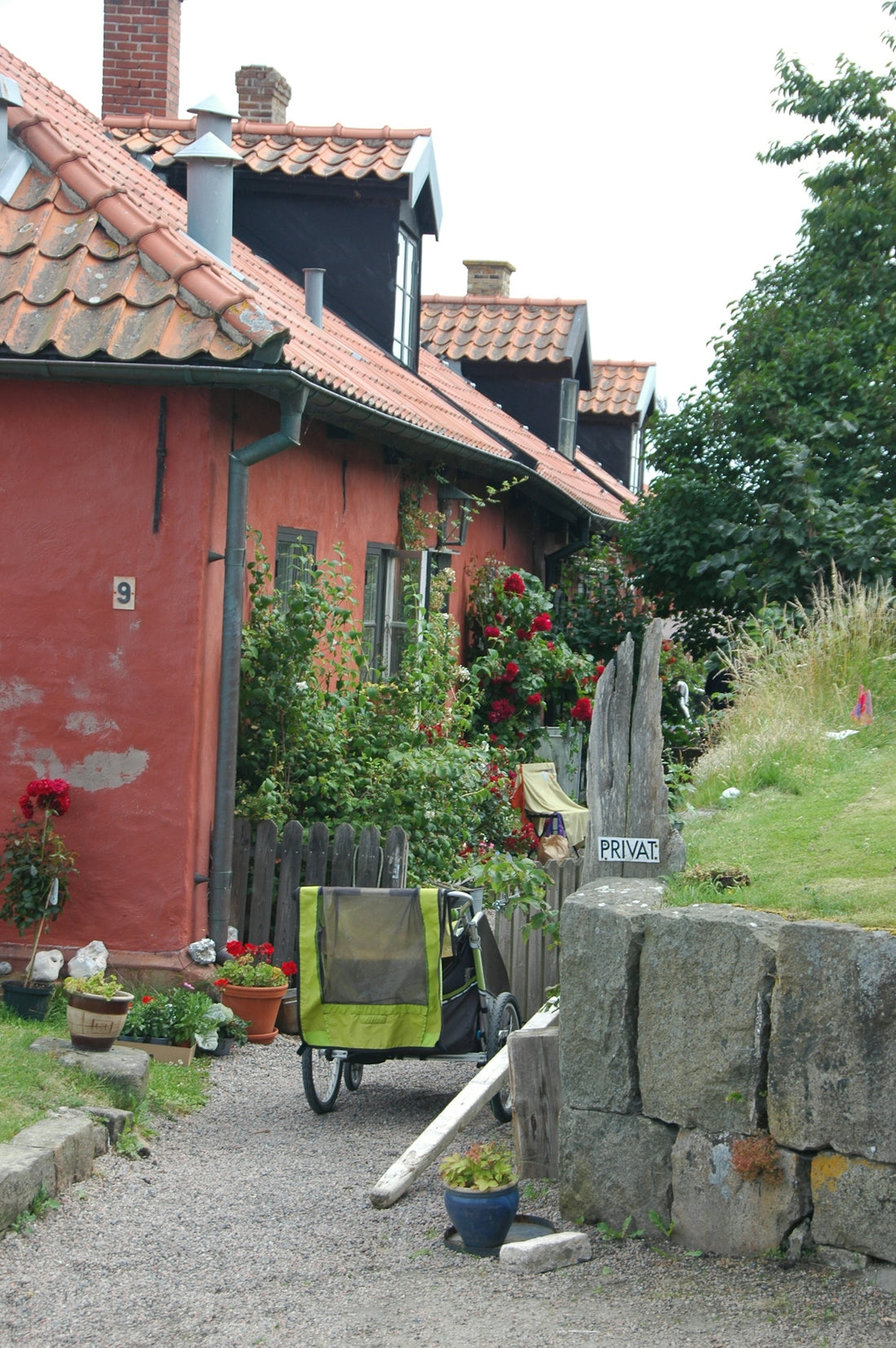 A red building with a red roof next to a stone wall