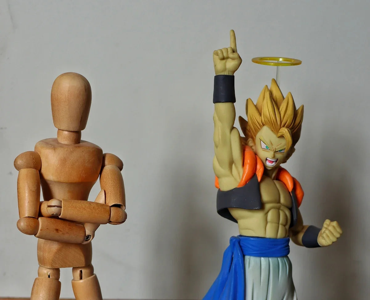 Två leksaksfigurer, en trädocka och en Dragon Ball-karaktär, mot neutral bakgrund hos Nerdbutiken.