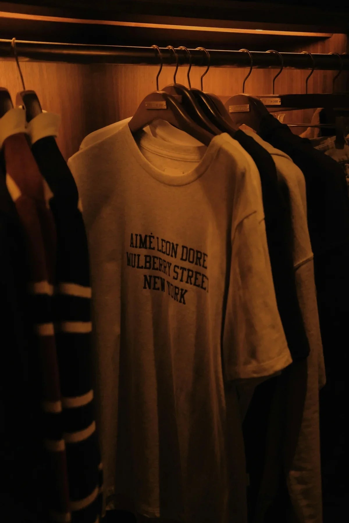 T-shirt med texten 'Aimé Leon Dore Mulberry Street New York' på klädhängare, nördprylar
