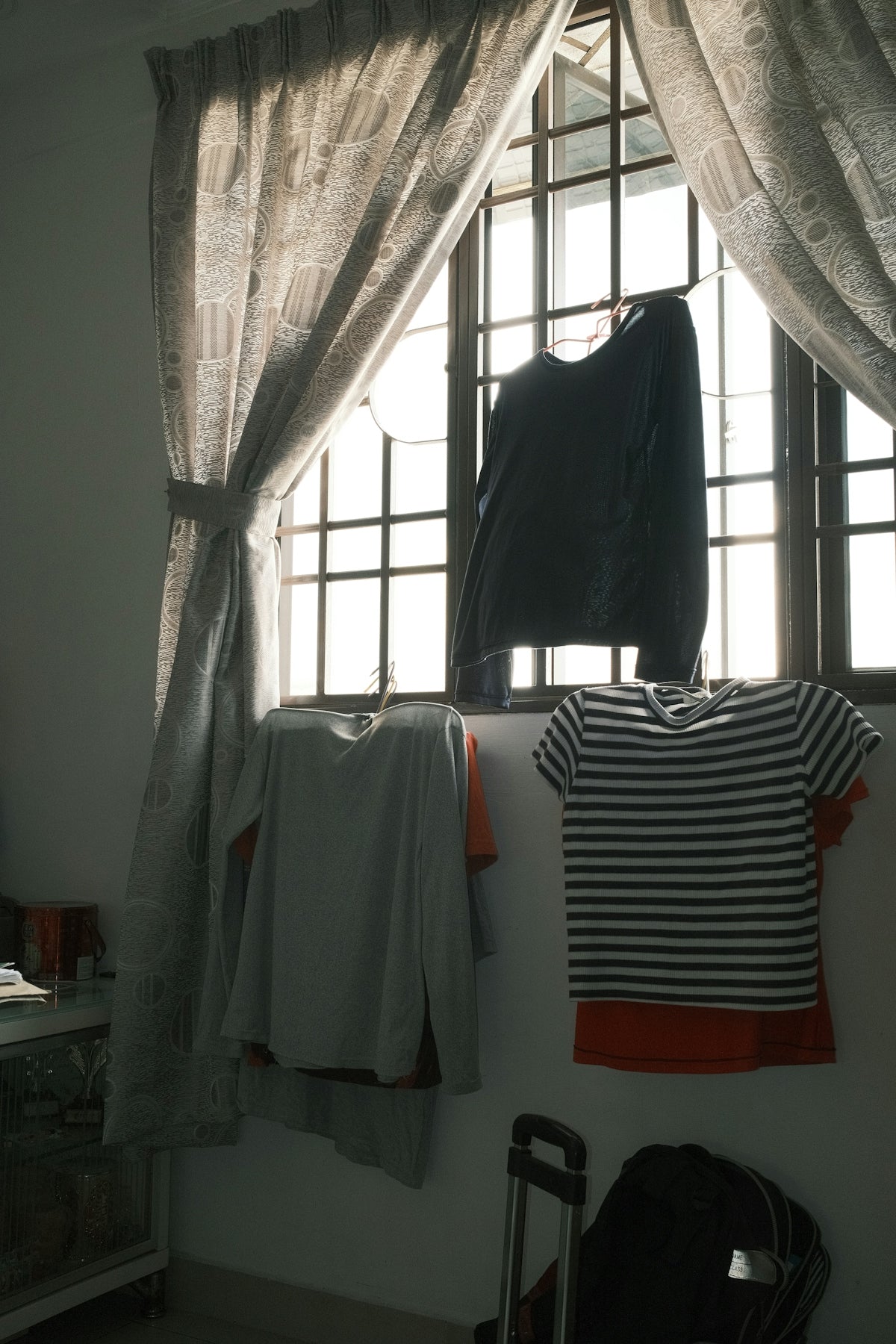 A room with a window and clothes hanging on a rack