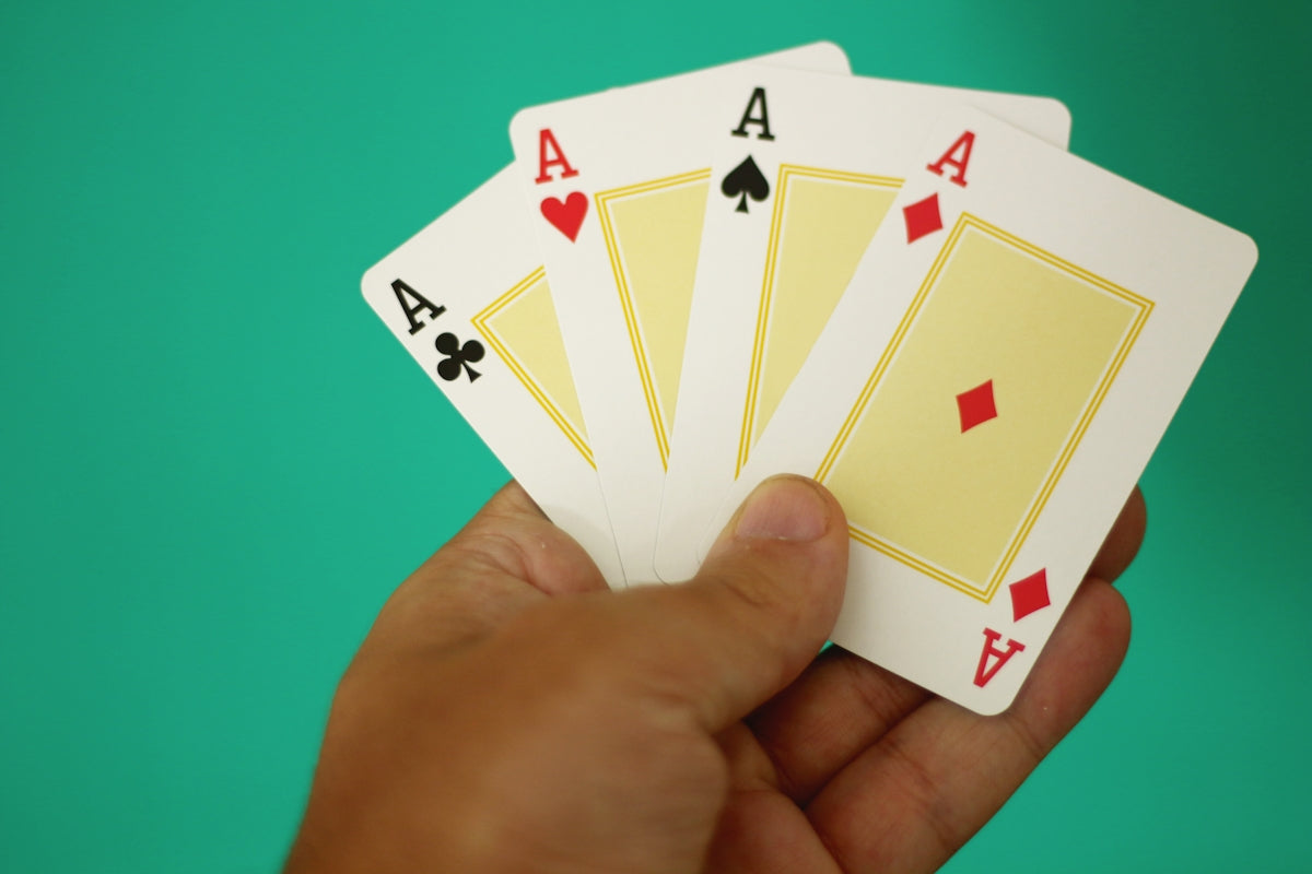 A hand holding four of a kind of playing cards