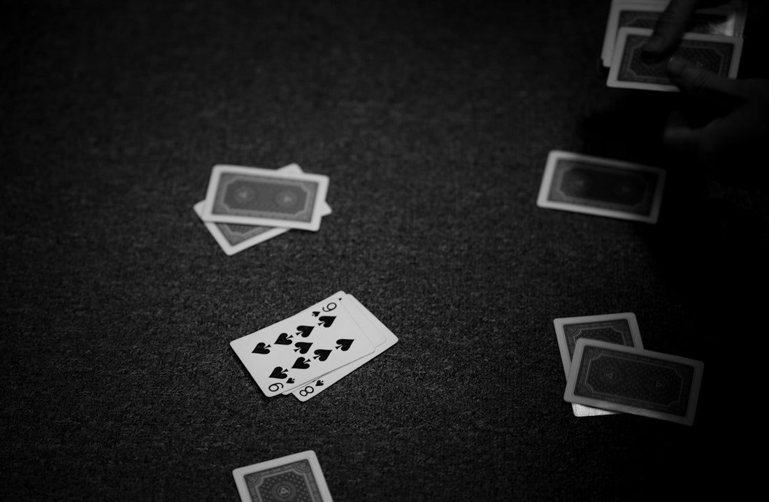 Playing cards are scattered on a dark surface.