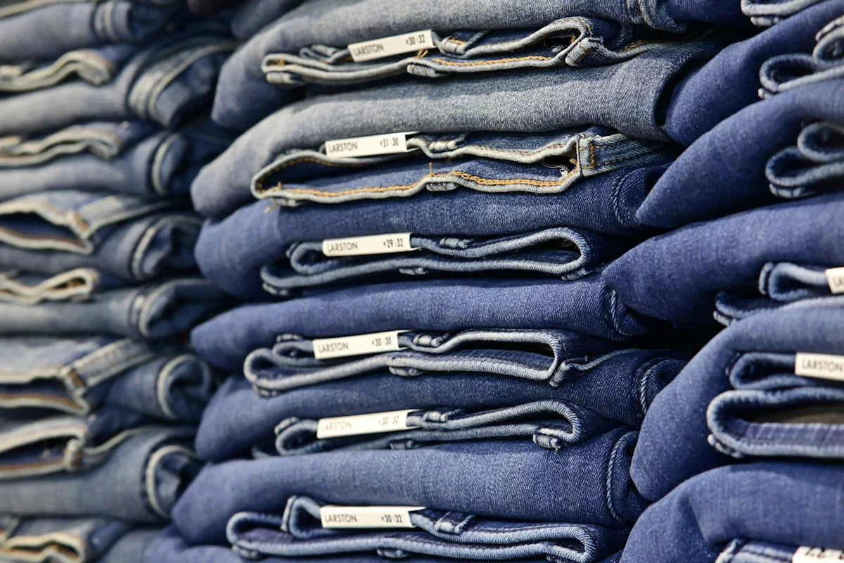 Staplar av vikta blå jeans i olika storlekar, denimkläder butik Nerdbutiken