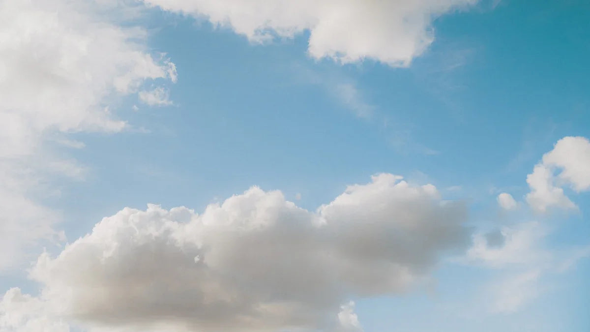 Fluffy clouds float across a bright blue sky.