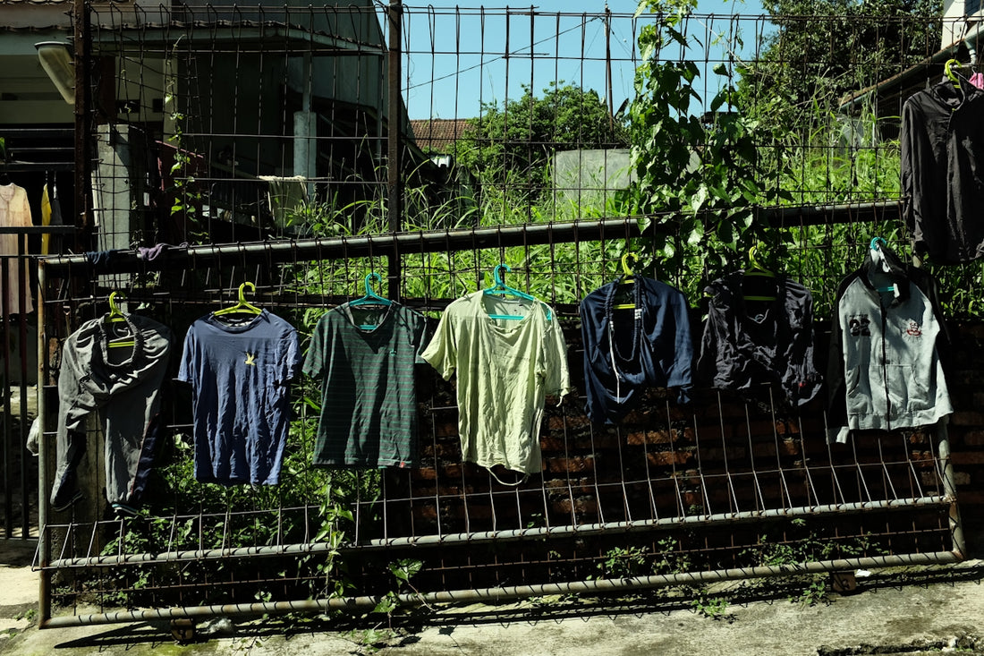Clothes hang on a fence outside.
