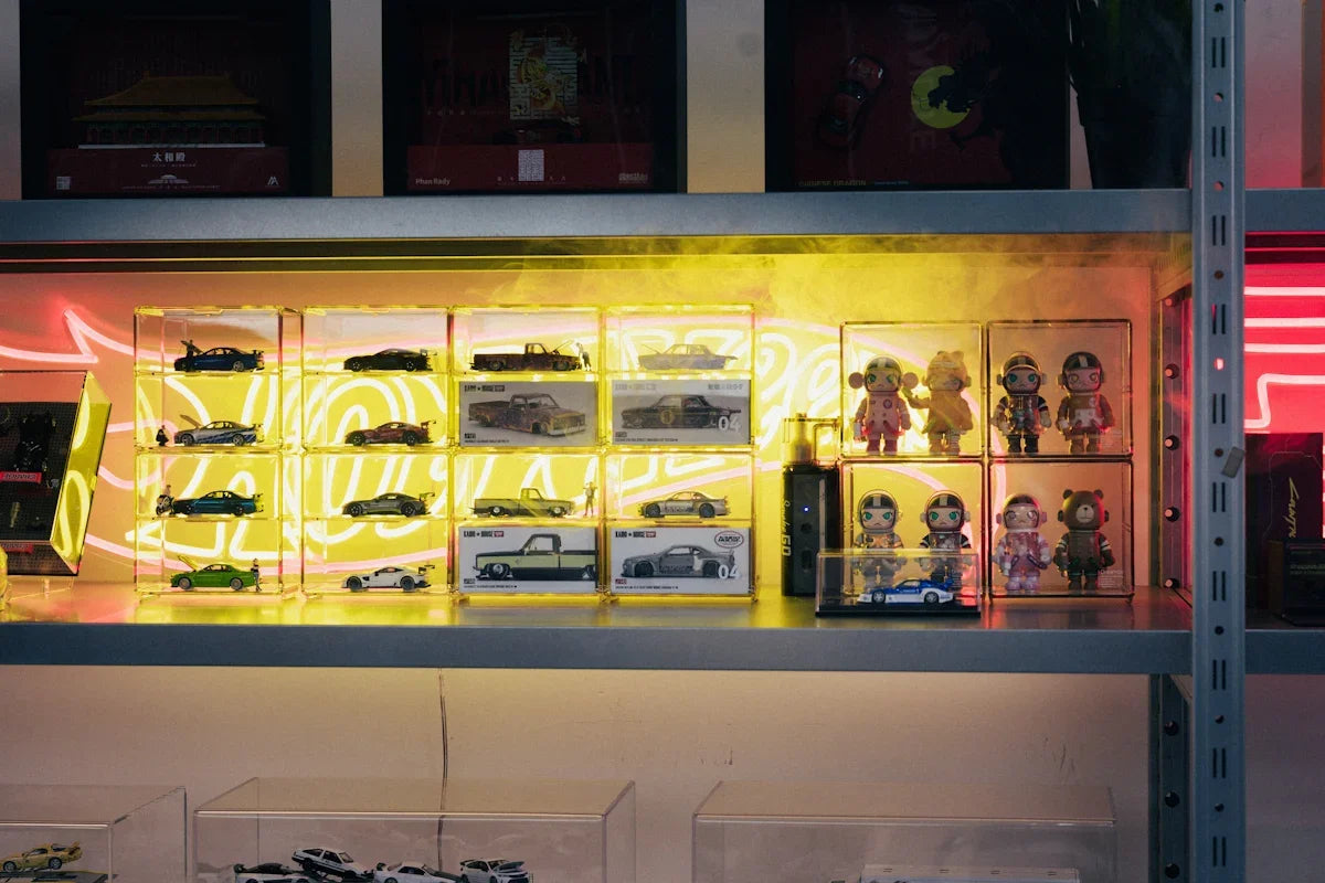 Hylla med samlarbilar och figurer i neonbelysning hos Nerdbutiken, perfekt för nördar.