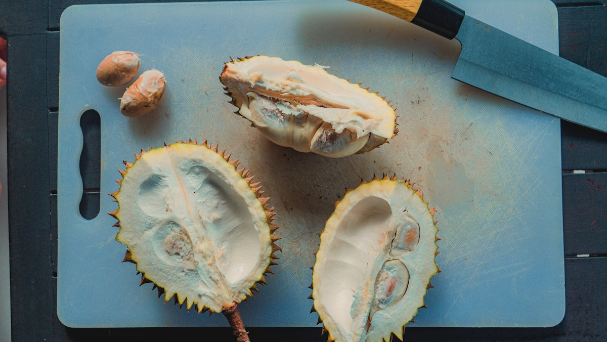 Durian fruit cut open with seeds on cutting board