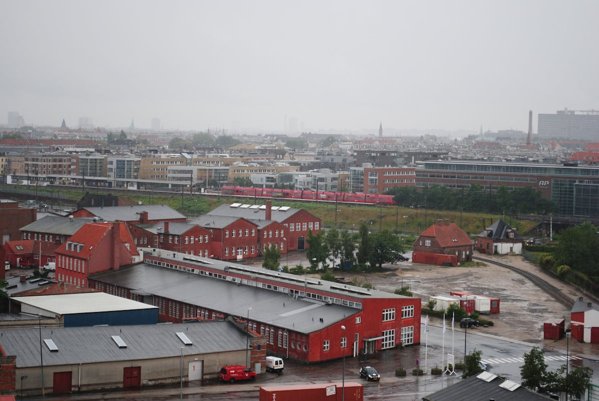 Overcast sky above industrial buildings and city skyline.