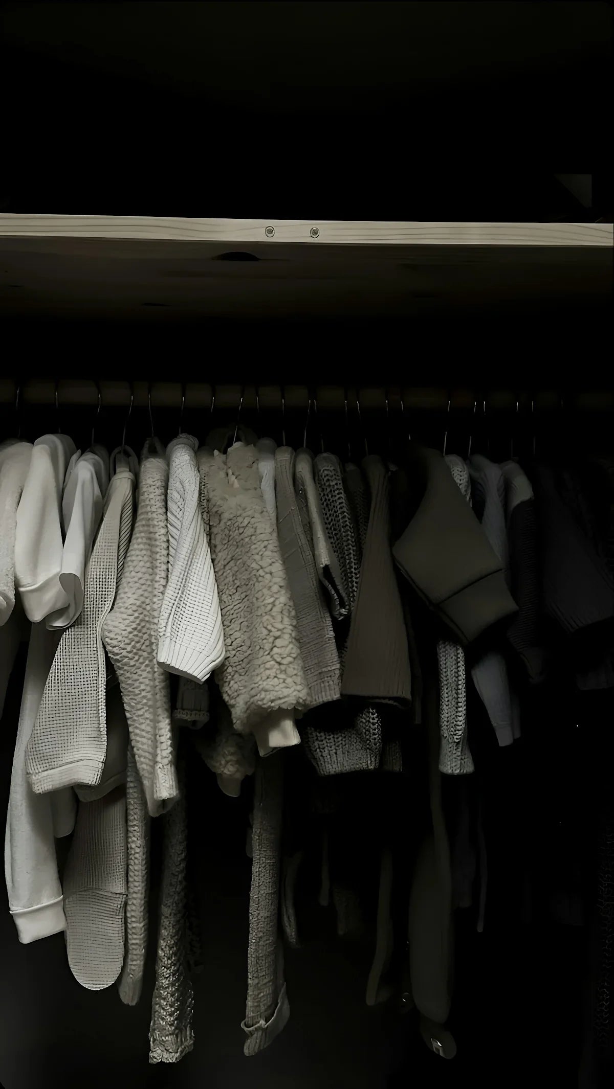 Grå och vita stickade tröjor på galge i en garderob, neutrala färger, modeinspiration