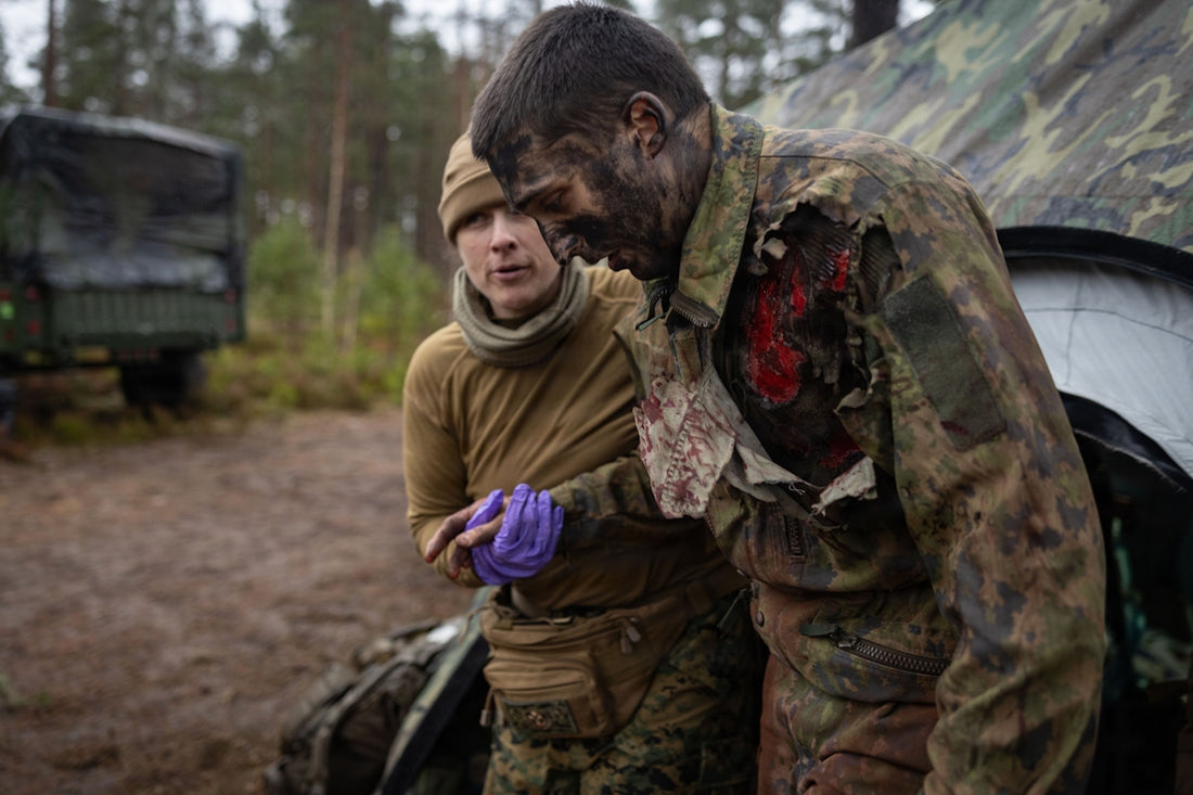 Medic tends to wounded soldier in forest camp